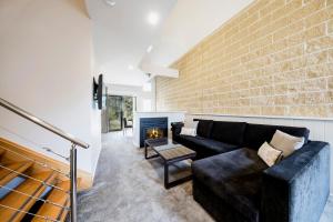 a living room with a couch and a fireplace at The Sebel Creswick Forest Resort in Creswick