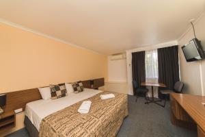 
a hotel room with two beds and a television at Hampton Villa Motel in Rockhampton
