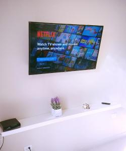 a television hanging on a wall above a white shelf at Latitude Adjustment in San Juan