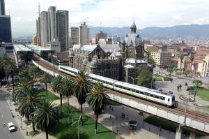 a train is crossing a bridge over a city at San Peter Apartments in Medellín