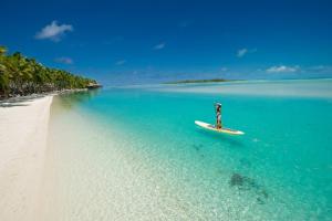a man riding a surfboard on top of a wave in the ocean at Aitutaki Lagoon Private Island Resort (Adults Only) in Arutanga