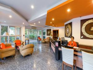 a woman sitting at a counter in a hotel lobby at Phuket Sea Resort SHA Extra Plus in Rawai Beach