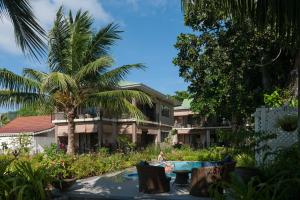 une personne assise sur des chaises en face d'un complexe dans l'établissement Le Repaire - Boutique Hotel & Restaurant, à La Digue