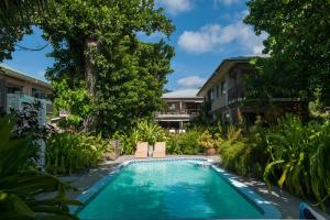 - une piscine dans une cour avec des arbres et des maisons dans l'établissement Le Repaire - Boutique Hotel & Restaurant, à La Digue