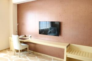 um quarto de hotel com uma televisão na parede em Jinling Yujingwan Hotel Changyi em Changyi