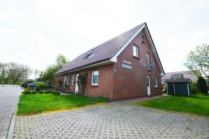 una casa de ladrillo rojo con entrada adoquinada en Lütt Holland, en Büsum