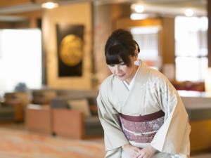 a woman in a kimono standing in a room at Hiranoya in Gamagori