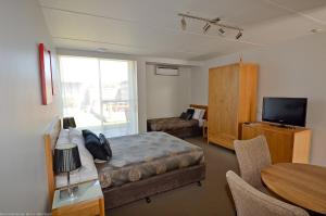1 dormitorio con 1 cama, TV y mesa en Riverside Ocean Grove, en Ocean Grove
