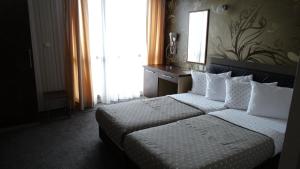 een slaapkamer met een bed met witte kussens en een raam bij Hotel Lazur in Kiten