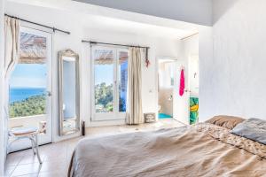 1 dormitorio con paredes blancas, ventanas grandes y 1 cama en Villa Orquidea - Amazing landscape view, en Santa Eulària des Riu