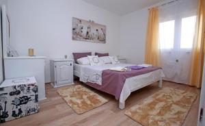 a white bedroom with a bed and a window at Luciano in Mravince
