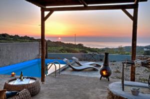 a patio with a fireplace next to a swimming pool at Gerakari Suites in Agia Pelagia