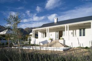 a white house with mountains in the background at La Cotte Orchard Cottages in Franschhoek