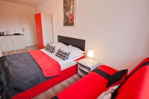 ブワディスワボボにあるBłękit Oceanuのベッドルーム(赤と黒のベッド1台、ソファ付)