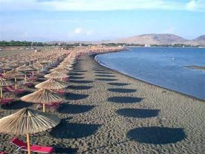 einen Strand mit vielen Sonnenschirmen, Stühlen und Wasser in der Unterkunft Flat Ergli in Velipojë