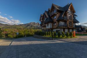 une grande maison en bois avec un toit en gambrel dans l'établissement Apartament Szymaszkowa Relax Ski Odkryj Zakopane, à Zakopane