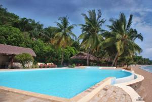 a swimming pool at a resort with palm trees at Anjiamarango Beach Resort in Nosy Be