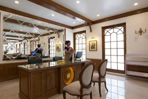 a woman standing at a counter in a room with chairs at Welcomheritage Ashdale in Nainital