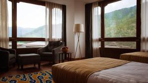a hotel room with a bed and chairs and windows at Osel Thimphu Bhutan in Thimphu