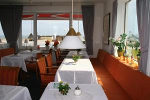 a restaurant with white tables and chairs and windows at Hanseat in Helgoland