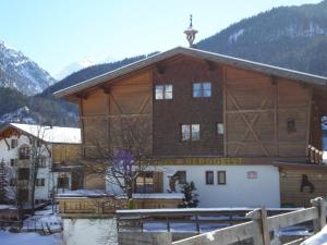 a large wooden building with snow in front of it at Pension Berggeist in Sölden