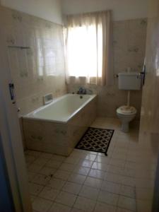a bathroom with a tub and a toilet and a window at Kuku Royal Lodge in Ndola