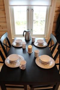 una mesa negra con platos y tazas y velas. en Camp Dronningkrona en Ålvundeid
