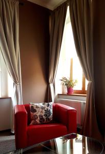 a red chair in a living room with a window at Hotel Merlot in Louny
