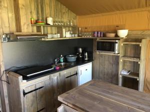 a kitchen with wooden cabinets and a counter top at Safaritent 't Kwedammertje in Kwadendamme