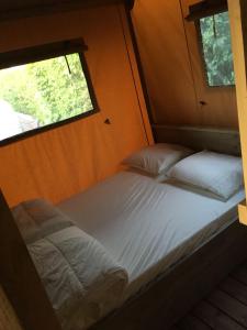 uma cama num pequeno quarto com uma janela em Safaritent 't Kwedammertje em Kwadendamme