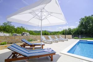 a group of lounge chairs and an umbrella next to a pool at Villa Katja in Omiš