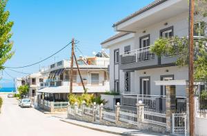 a white house with balconies on a street at Saint Lucas Suites in Nea Potidaea