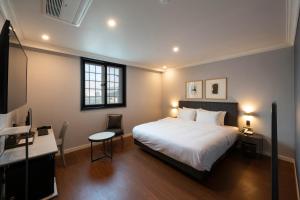 a bedroom with a bed and a table and a desk at Brown-Dot Hotel Gupo in Busan