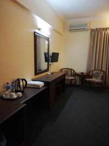una camera d'albergo con specchio, scrivania e sedie di Hotel Damai a Parit Buntar