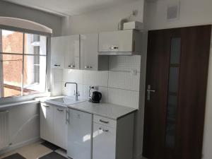 biała kuchnia ze zlewem i oknem w obiekcie Apartament Matejki 7/4 w Zielonej Górze +3 zdjęcia