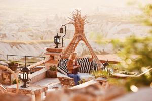 una mujer sentada en una hamaca en un balcón con vistas en Rox Cappadocia, en Uchisar