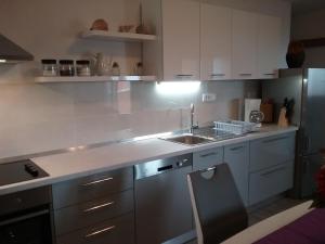 una cocina con armarios blancos y fregadero en Apartment Willy en Komiža