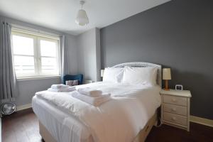 a bedroom with a white bed with towels on it at Holyrood Park - Carparking included! in Edinburgh
