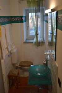 baño con aseo y lavabo y ventana en Il Grillo Parlante, en Monforte dʼAlba