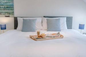 a tray of food on top of a white bed at Serendipity, an apartment on the high street! in Aldeburgh