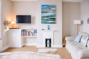 a living room with a couch and a tv at Serendipity, an apartment on the high street! in Aldeburgh