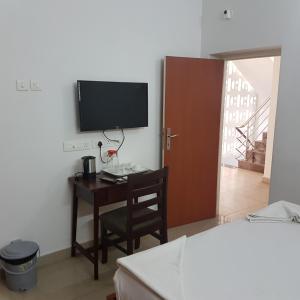 a bedroom with a desk with a television and a bed at Surag Residency in Tiruchirappalli