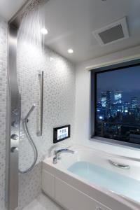 a bathroom with a bath tub and a window at Osaka View Hotel Honmachi in Osaka