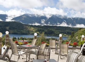 a patio with tables and chairs and a view of a mountain at Pension Guggenbichler in Seeboden