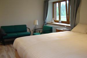a bedroom with a bed and two chairs and a window at Notre Cachette in Biffontaine