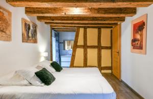 - une chambre avec un lit doté de draps blancs et d'oreillers verts dans l'établissement Porte des Pucelles, à Ribeauvillé