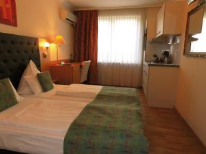 um quarto de hotel com uma cama grande e uma cozinha em Aparthotel Guzulka & Restaurant em Berlim