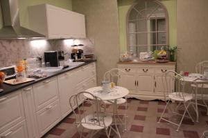 cocina con armarios blancos, mesa y sillas en Aitna B&B, en Catania