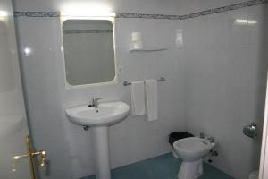 a white bathroom with a sink and a toilet at Apartamentos Astoria - Benidorm in Benidorm