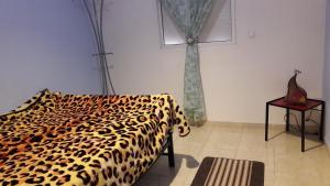 Un dormitorio con una cama con estampado de leopardo y una mesa en Dar Diafa, en Agadir